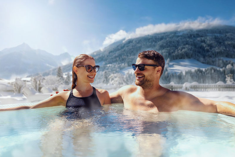 Couple sitting in a hot tub escaping the cold winter